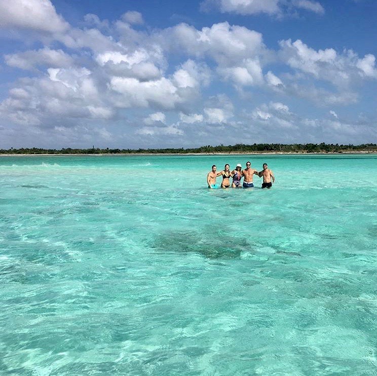 Familia caminando en el agua turquesa cristalina de una playa privada en Cozumel