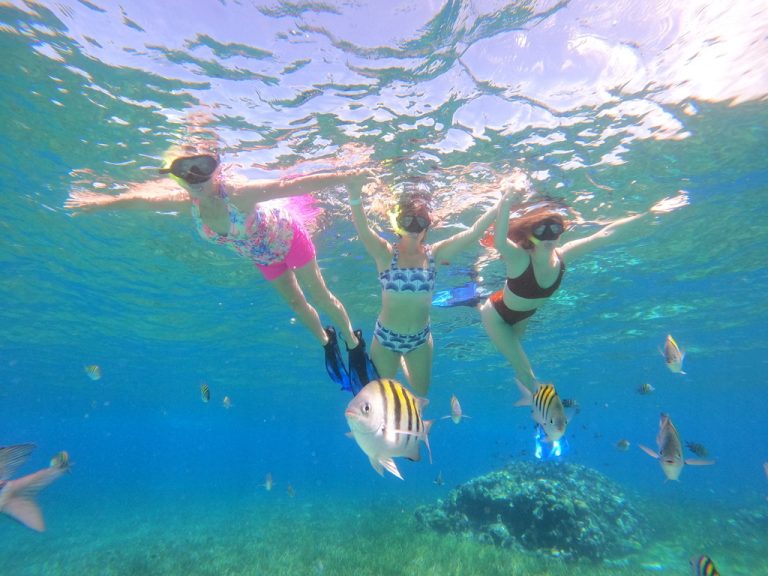 Familia haciendo snorkel junta en el agua cristalina de Cozumel