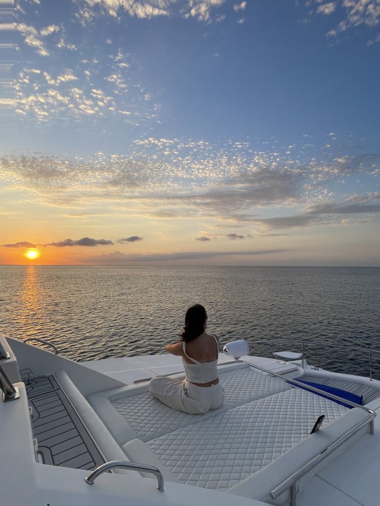 Guest watching the sunset from the bow of a catamaran