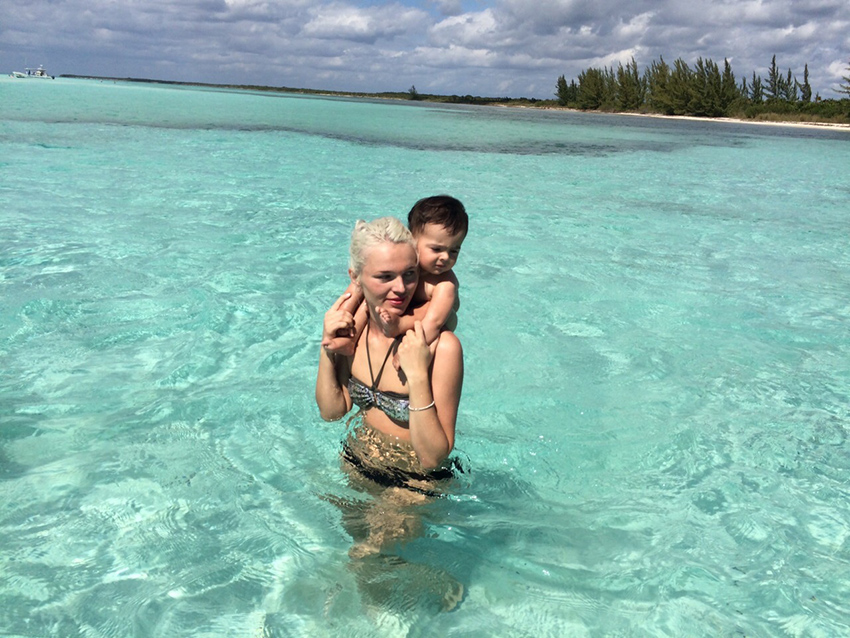 Mamá e hijo jugando en agua cristalina poco profunda en una playa privada de Cozumel