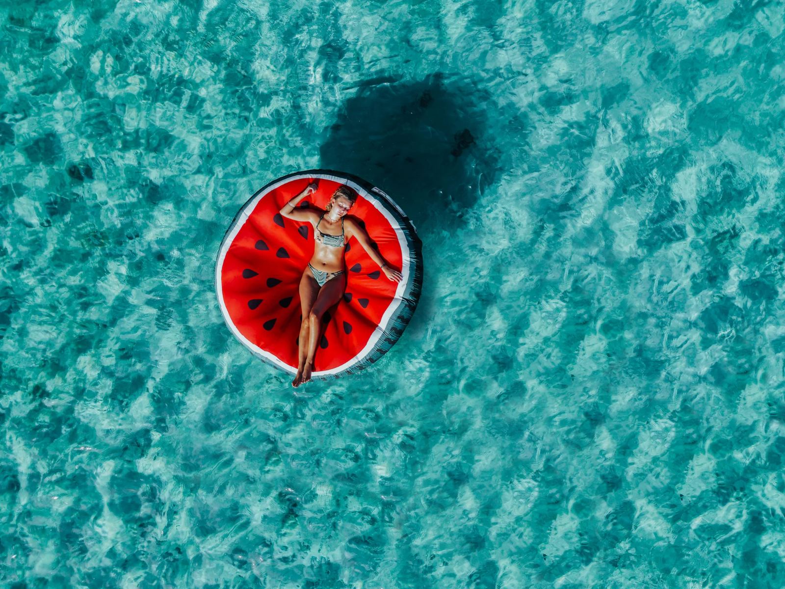 Invitada descansando en un flotador en agua turquesa frente a una playa privada en Cozumel