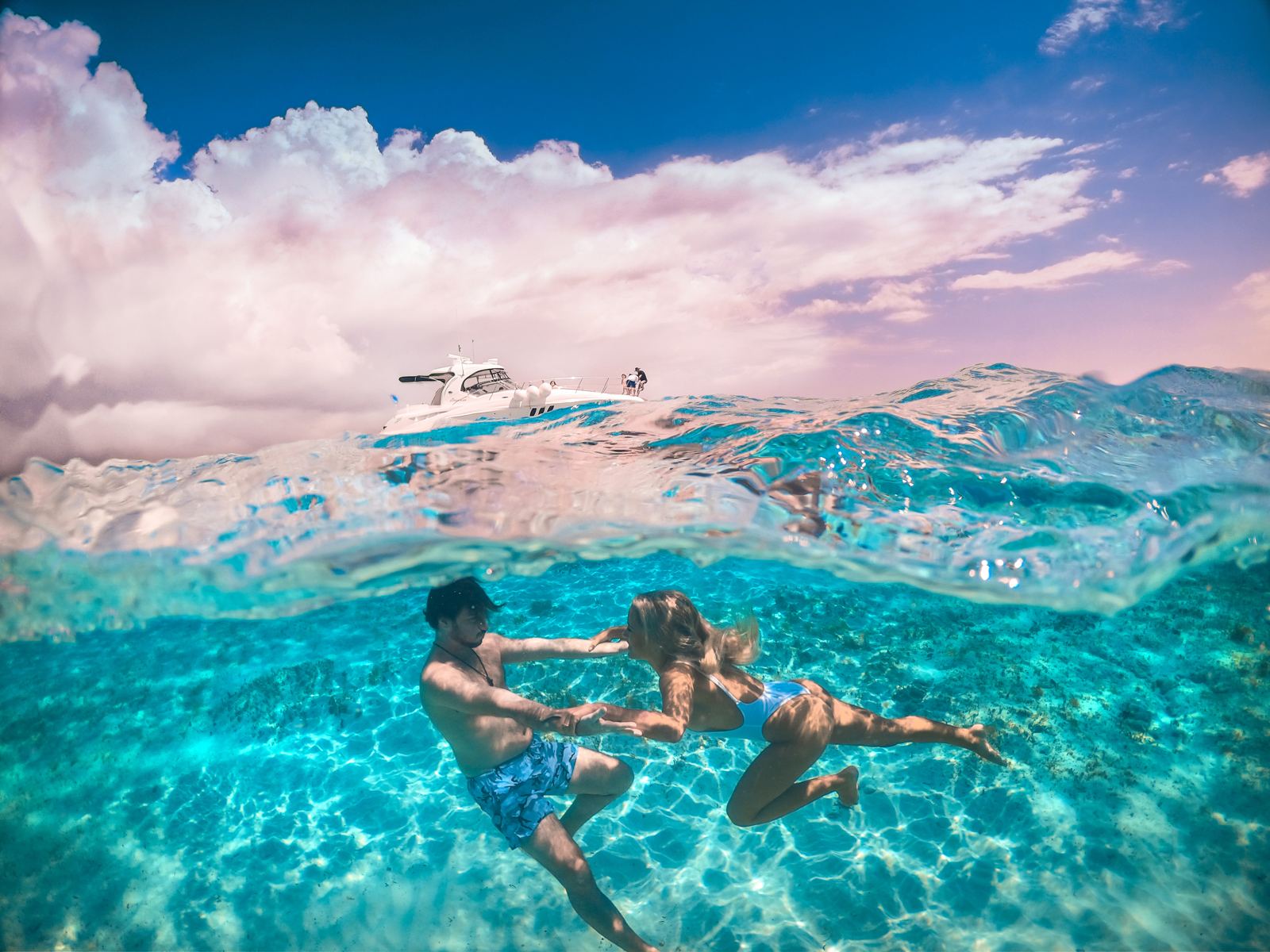 Couple swimming beside the boat in clear water