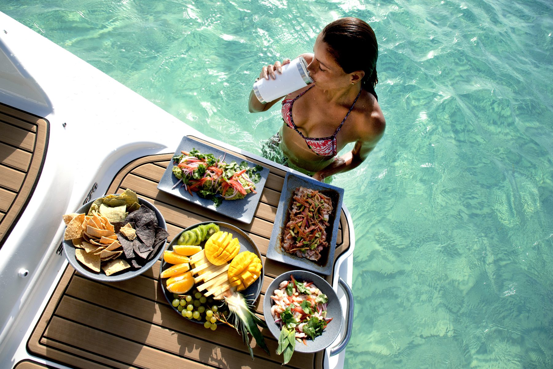 Woman in the water with fresh food platters at the Sea Ray 27 swim platform