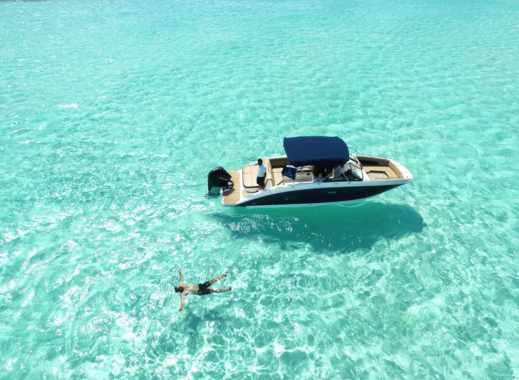 Guest floating beside the Sea Ray 27 in clear Cozumel water